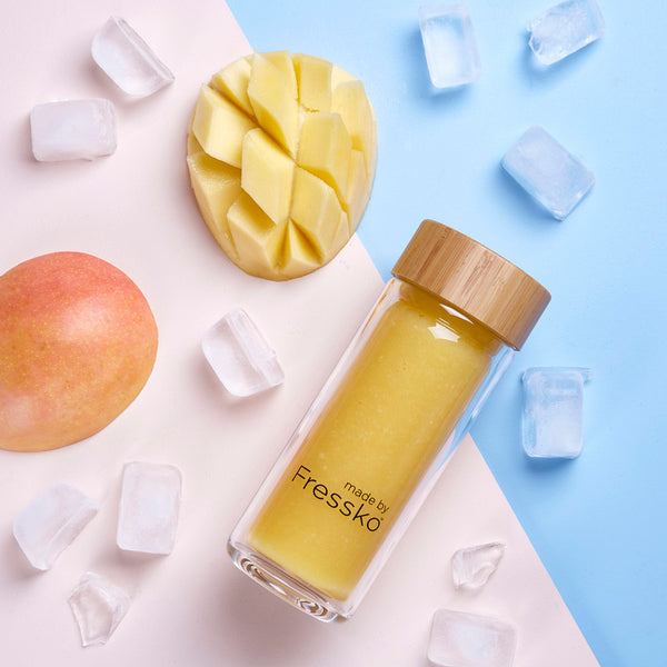 Fressko RISE glass flask with mango daiquiri inside surrounded by ice and mangos