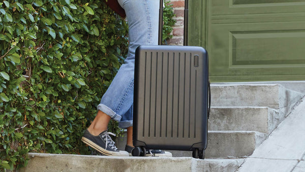Girl holding black suitcase on stairs