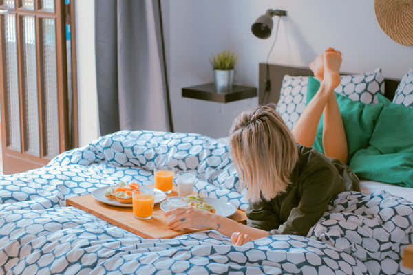 Woman relaxing on bed with orange juice and food